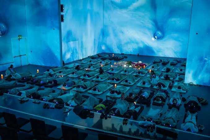Participants lying on mats in a dimly lit room with blue lighting projection during a Breath Portal session.